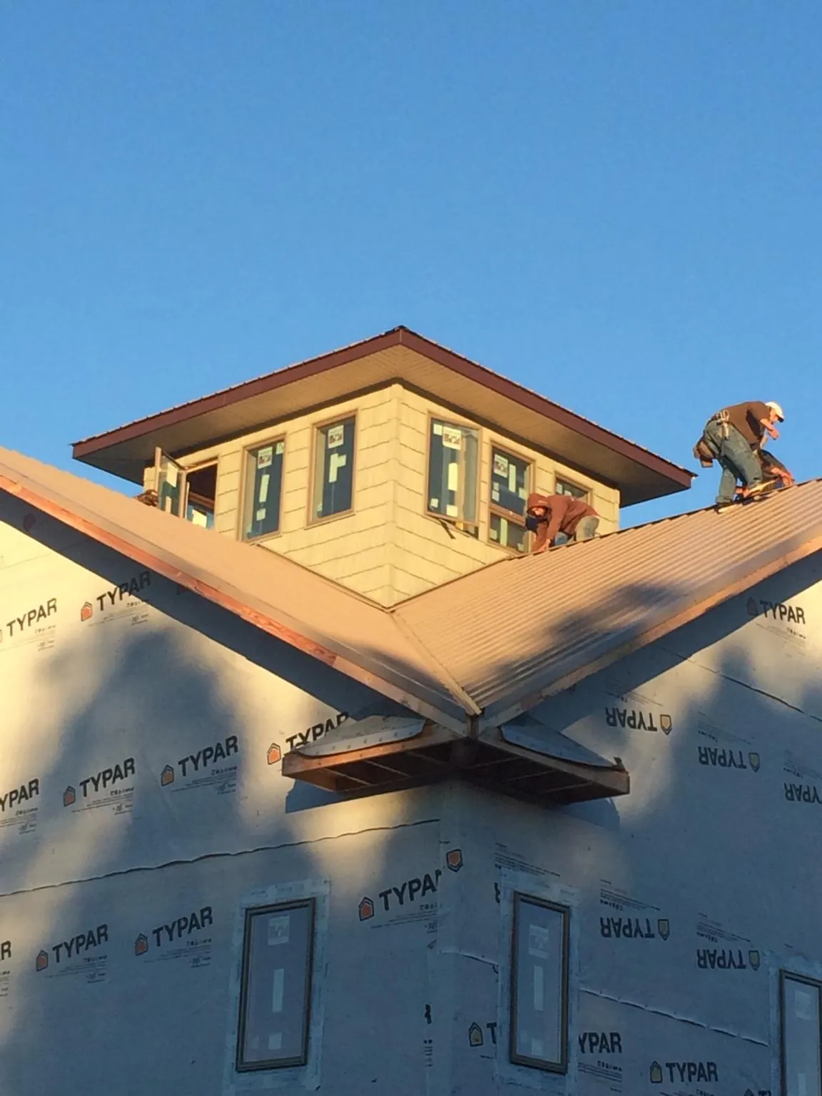 Roofers working around a rooftop cupola on a new metal roof at sunset — Roof Waterproofing in Bristol by Roofing Brothers